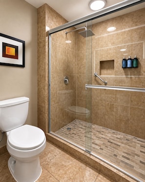 A modern bathroom with a glass-enclosed shower, a white toilet, and a framed picture on the wall.