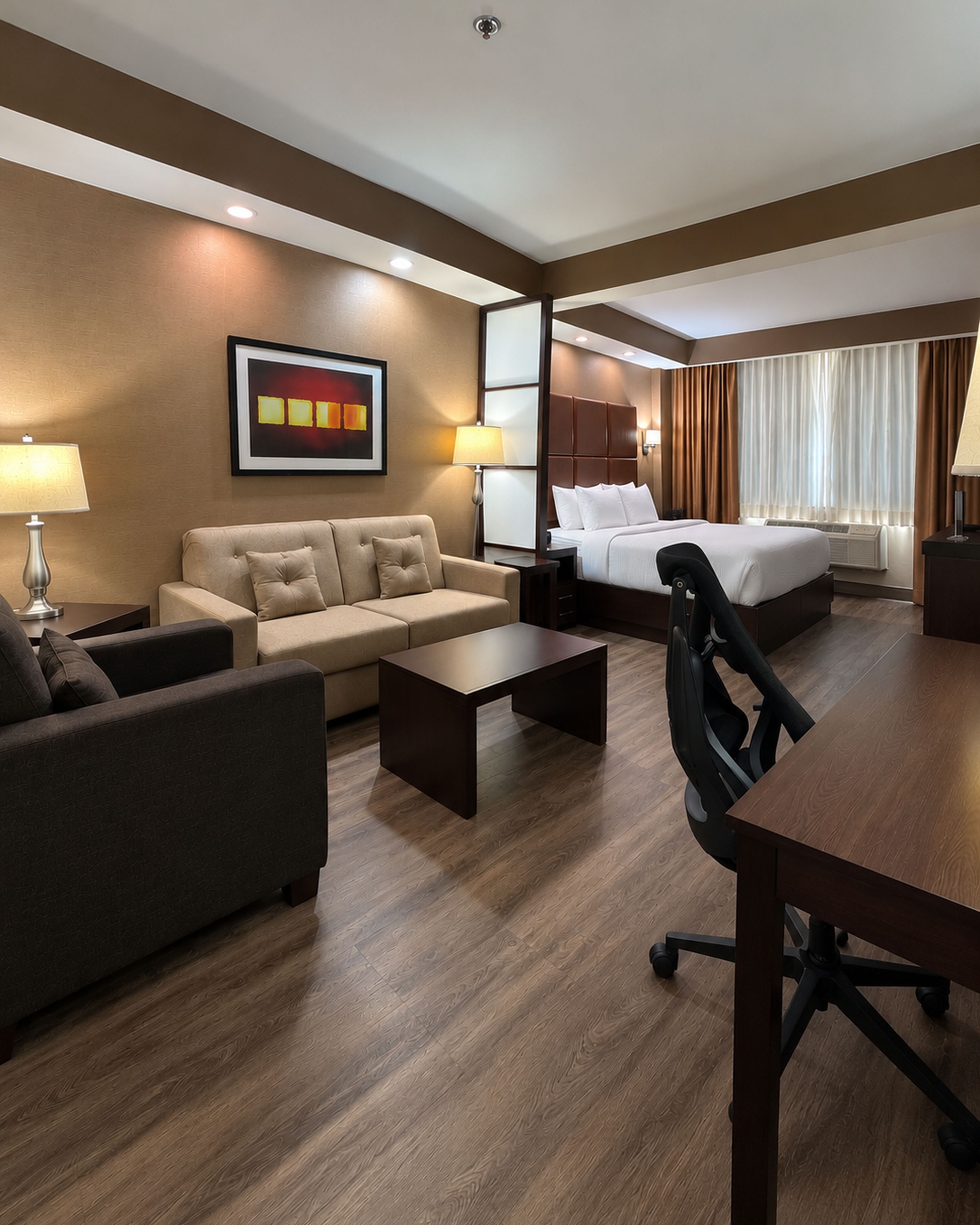 Una habitación de hotel con cama, sofá, escritorio y una silla.
