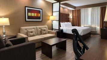 Una habitación de hotel con cama, sofá, escritorio y una silla.