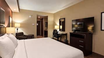Una habitación de hotel con una cama grande, un escritorio, una silla, un televisor y un espejo.