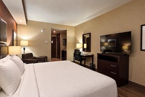 Une chambre d’hôtel avec un grand lit, un bureau, une chaise, une télévision et un miroir.
