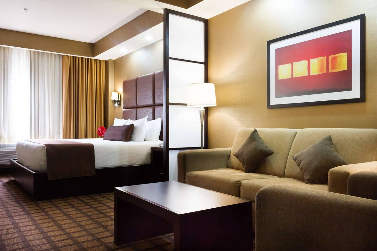Ein Hotelzimmer mit Bett, Sofa, Couchtisch und einem Gemälde an der Wand.