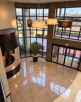 A lobby with large windows, a reception desk, and a potted plant.