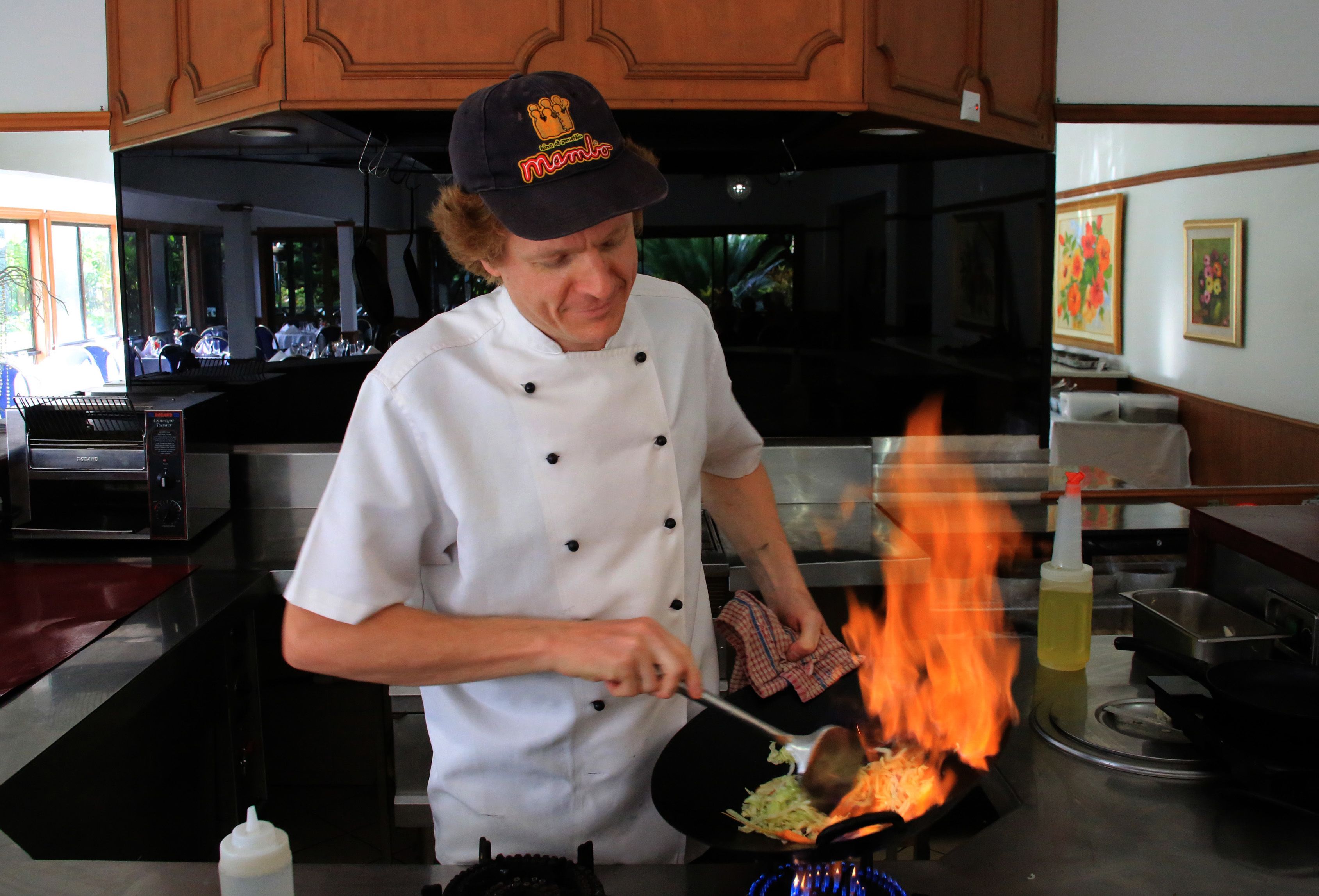 A chef cooking with flames in a professional kitchen.