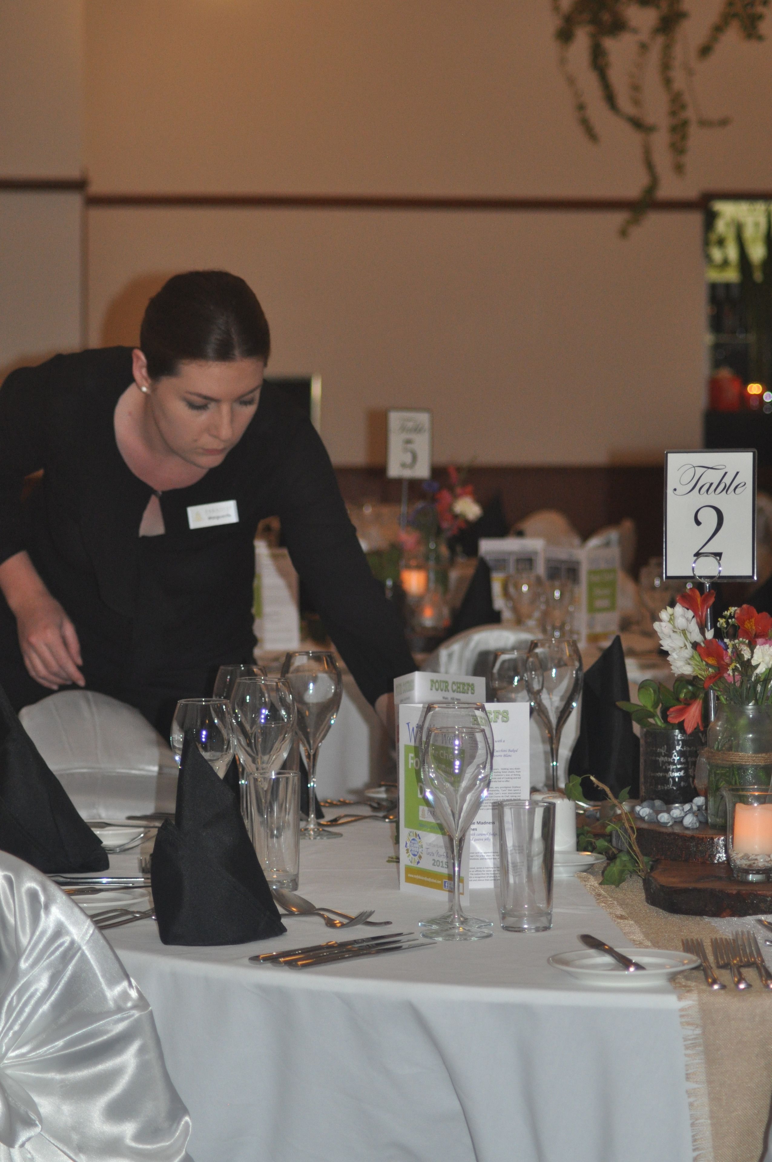 A table set for a formal event with a name tag, wine glasses, and a table number sign.