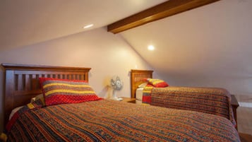 A bedroom with two beds, wooden headboards, and a sloped ceiling.