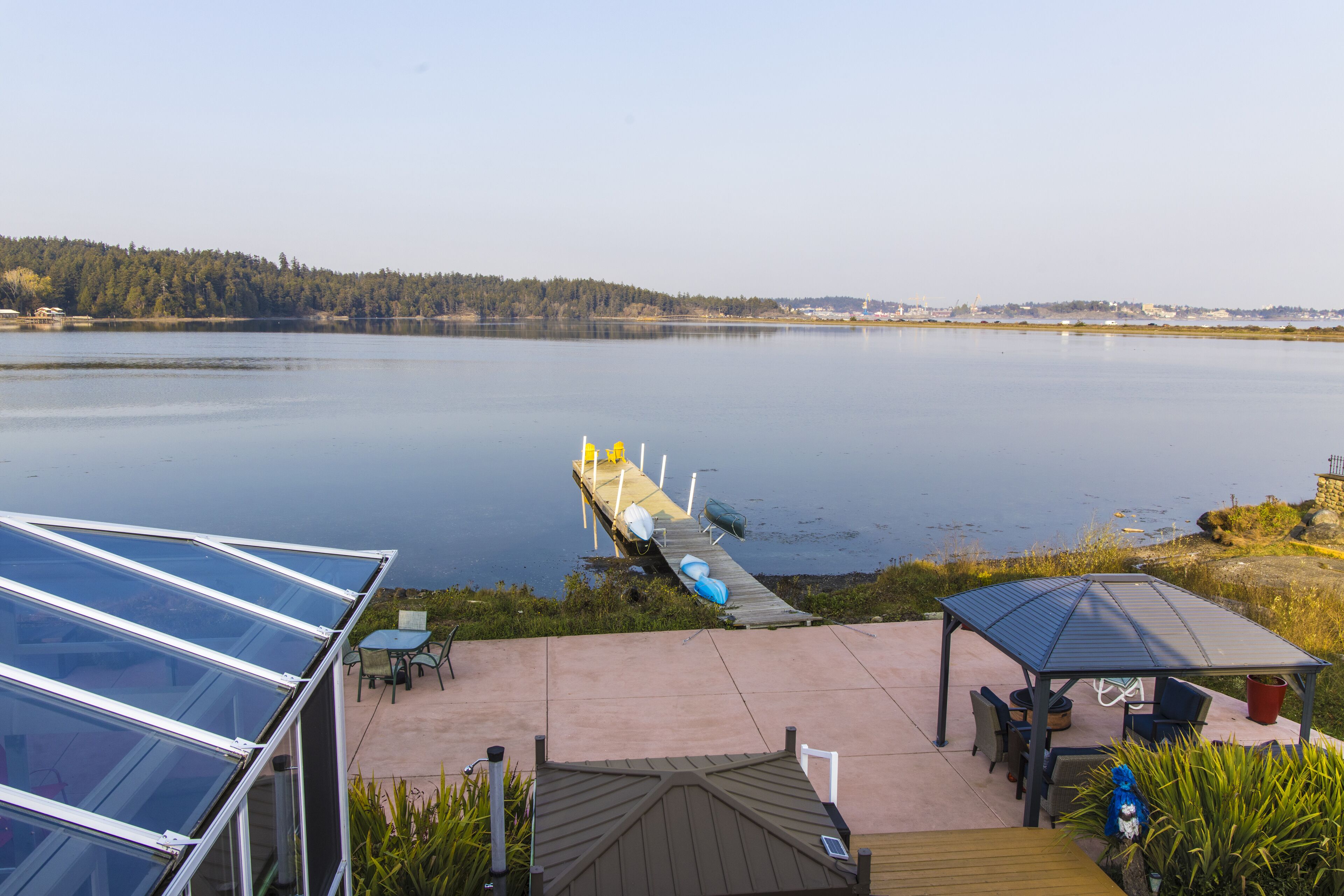 A lakeside patio with a gazebo, a covered seating area, and a dock extending into the water.
