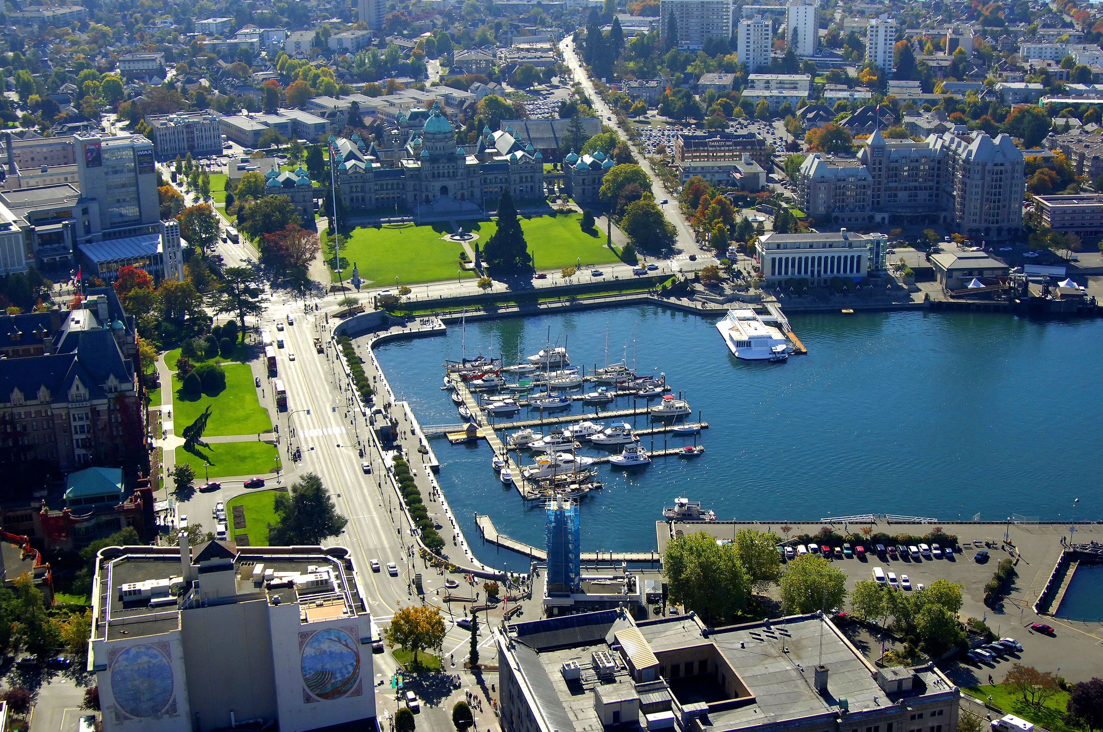 Vue aérienne d’une ville avec un port de plaisance, des immeubles et un grand espace vert aménagé en parc.