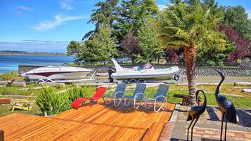 Una terraza de madera con sillones de descanso, un bote y flamencos decorativos.