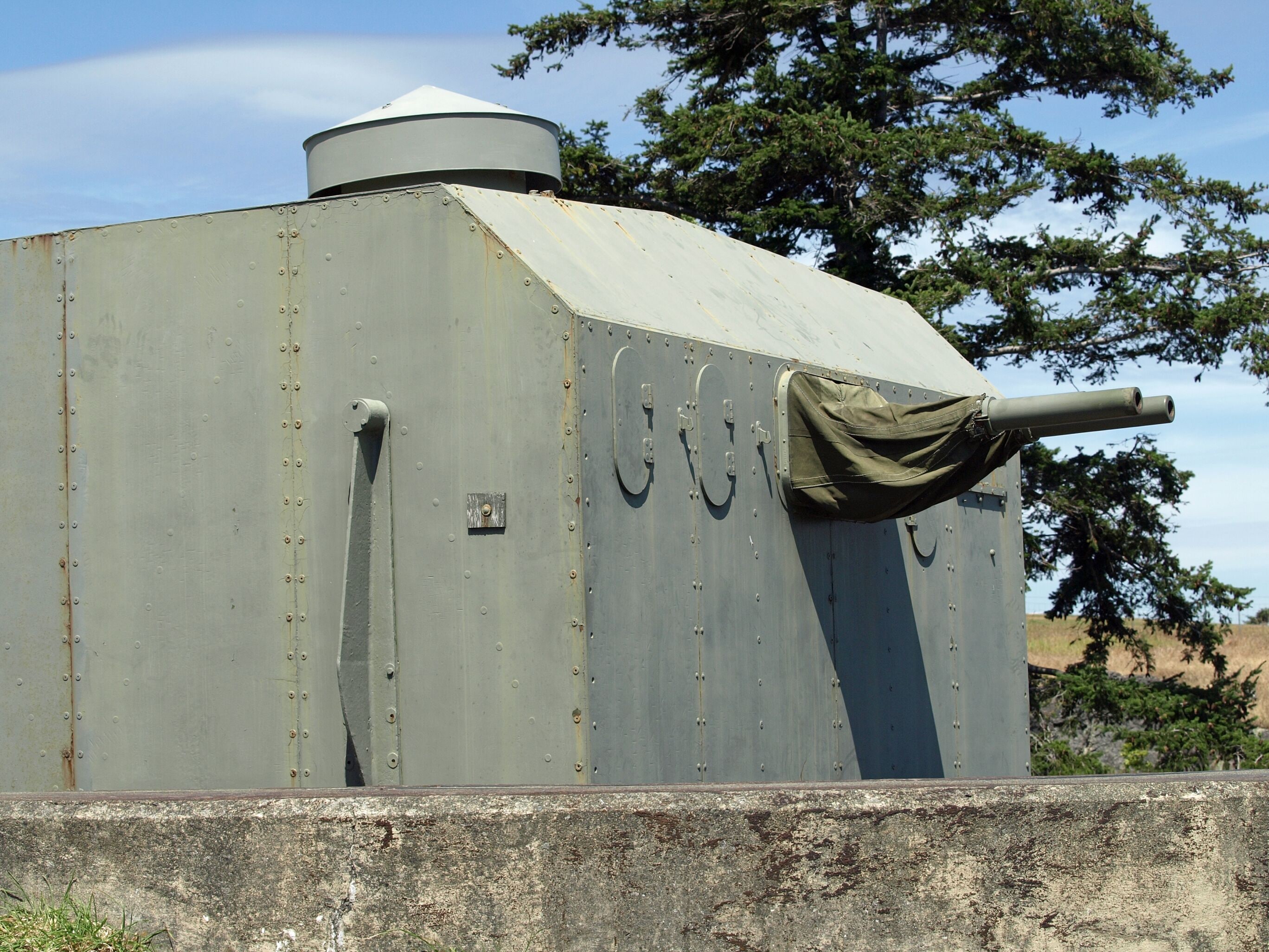 A large, cylindrical metal structure with a conical top, a mounted gun, and a small door.