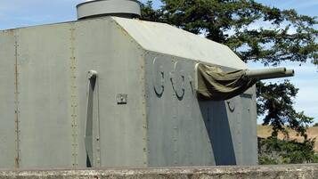 A large, cylindrical metal structure with a conical top, a mounted gun, and a small door.