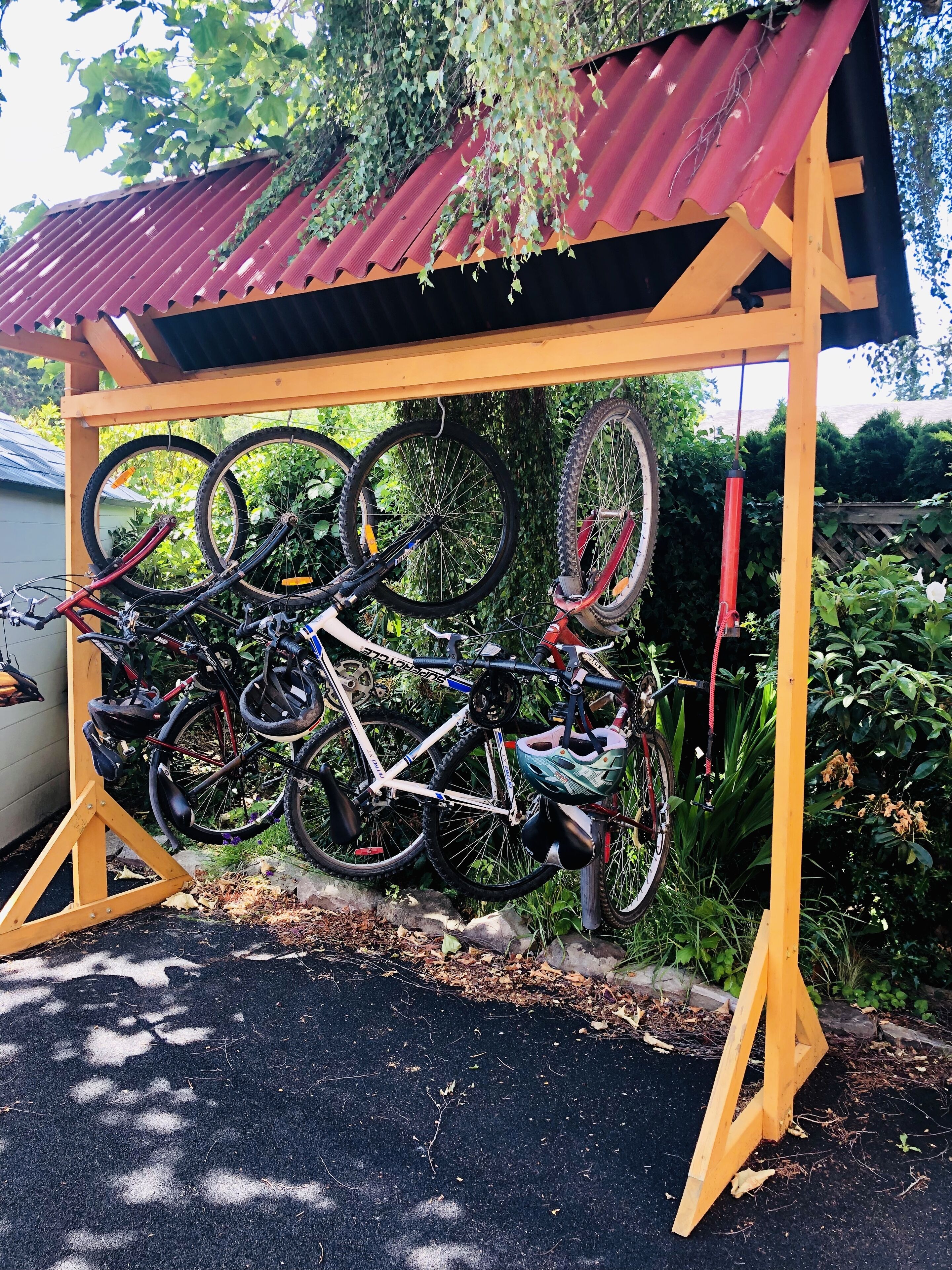 Un aparcaciclos con varias bicicletas estacionadas bajo una estructura de madera con techo rojo.