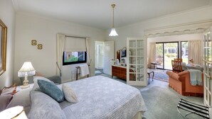 Un dormitorio con cama, cómoda, televisión y balcón con mesa y sillas.
