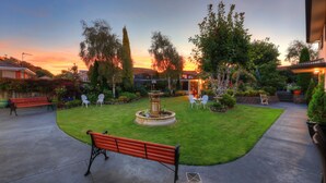 Un jardín bien cuidado con una fuente, bancos y mobiliario para exteriores.