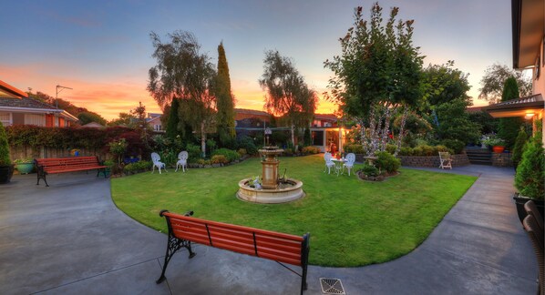 A well-maintained garden with a fountain, benches, and outdoor seating.