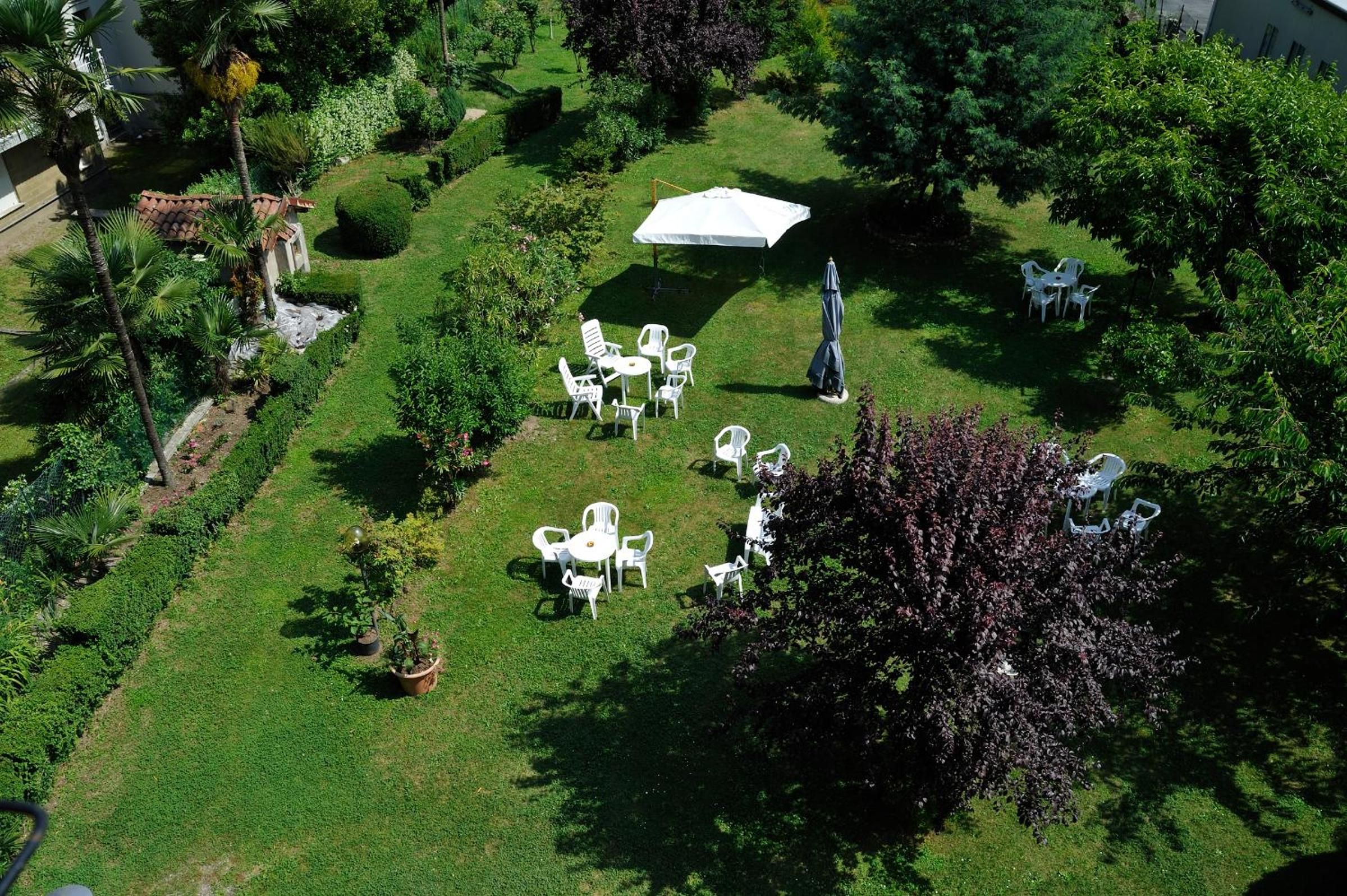Ein gepflegter Garten mit Außenmöbeln, darunter Tische und Stühle, und einem überdachten Bereich.