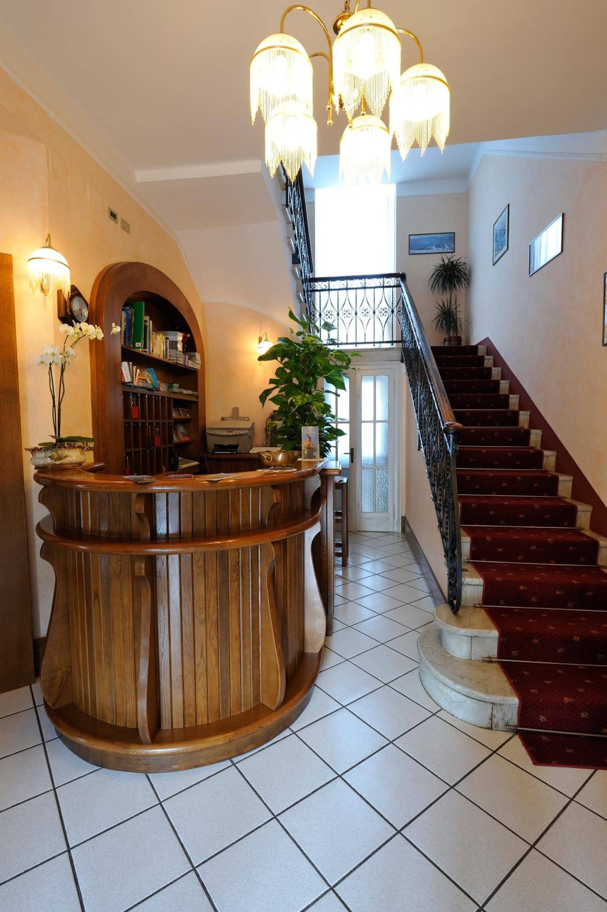 Una zona de recepción con un mostrador de madera, una escalera y un candelabro.