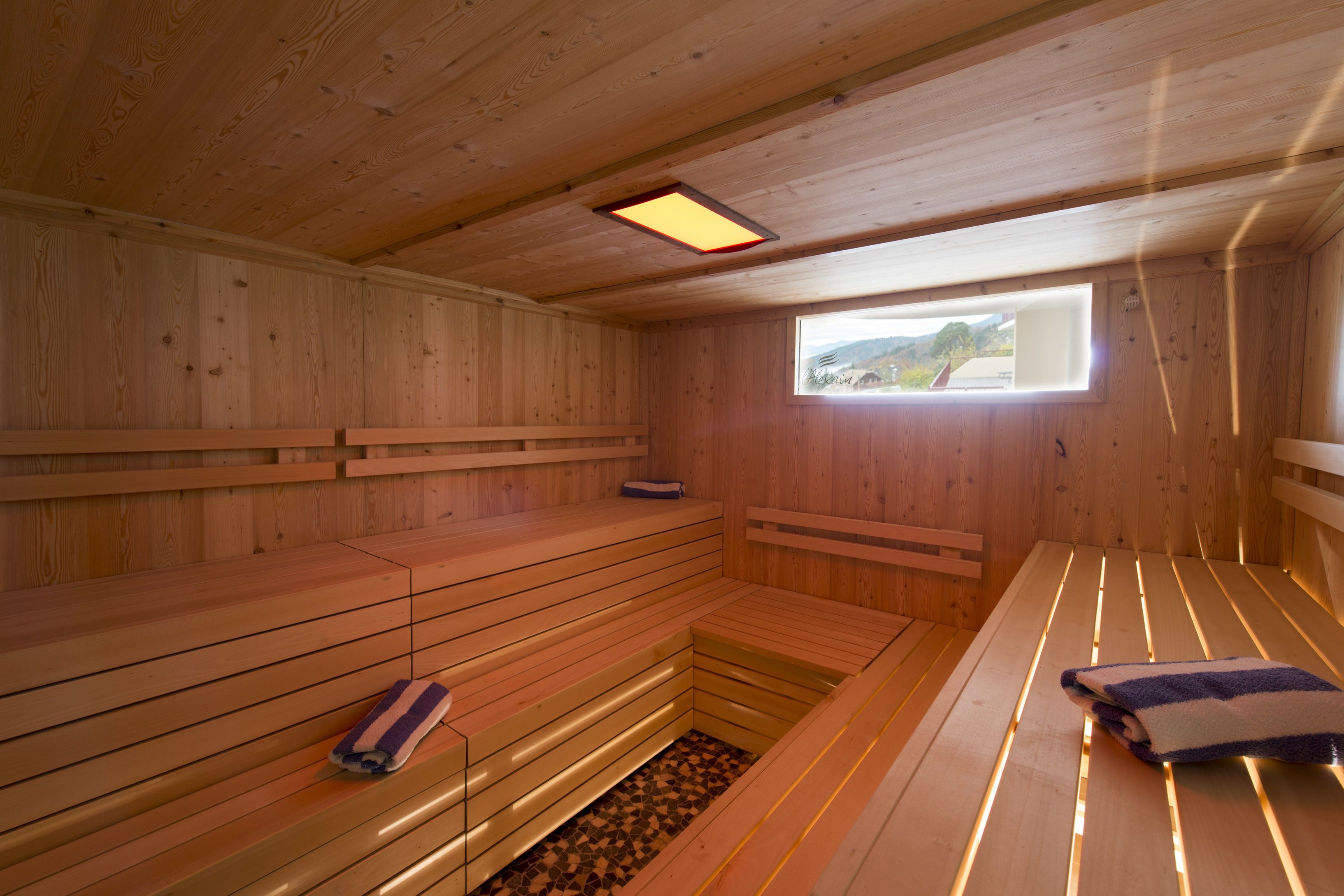 Una sauna de madera con bancos y una pequeña ventana.