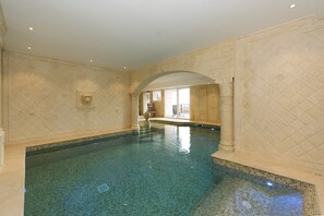 Una piscina interior con paredes de azulejos y agua de color azul claro.