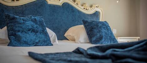 Una cama con un cabecero decorativo, dos almohadas y una mesita de noche con una lámpara.
