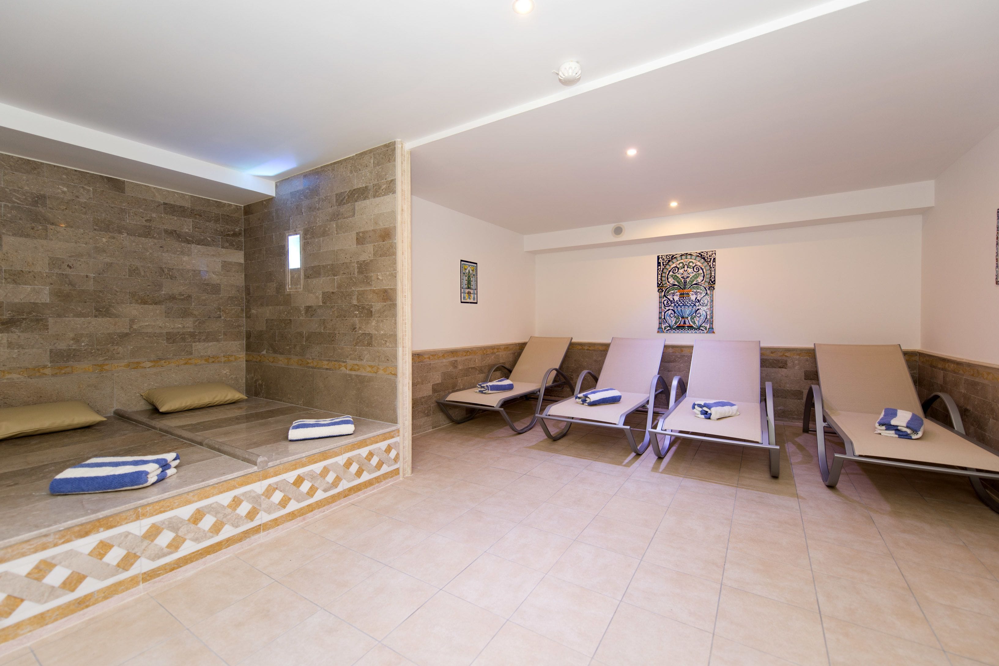 A spa area with massage tables, towels, and a decorative wall.