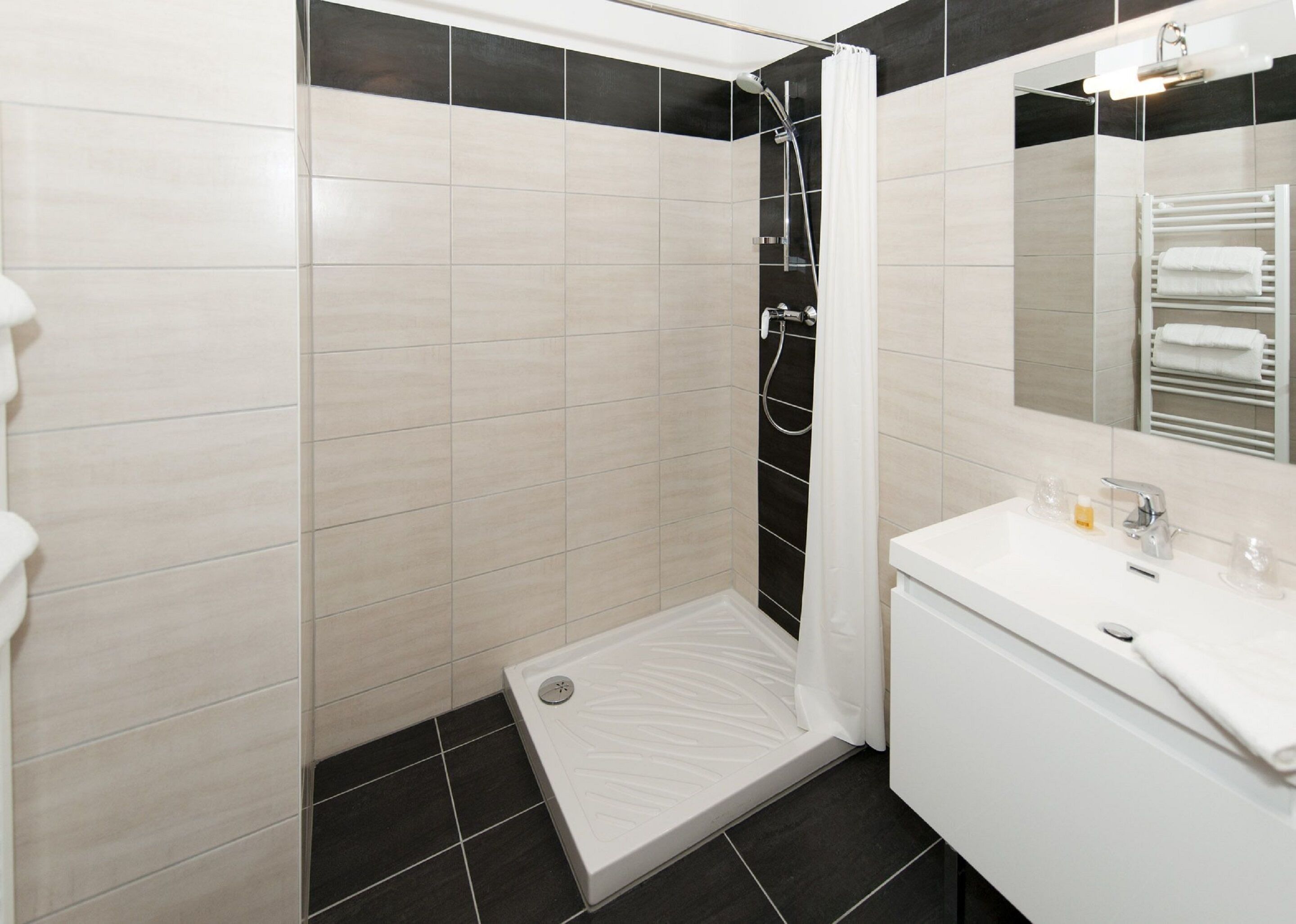 Un baño moderno con ducha, lavamanos y espejo.