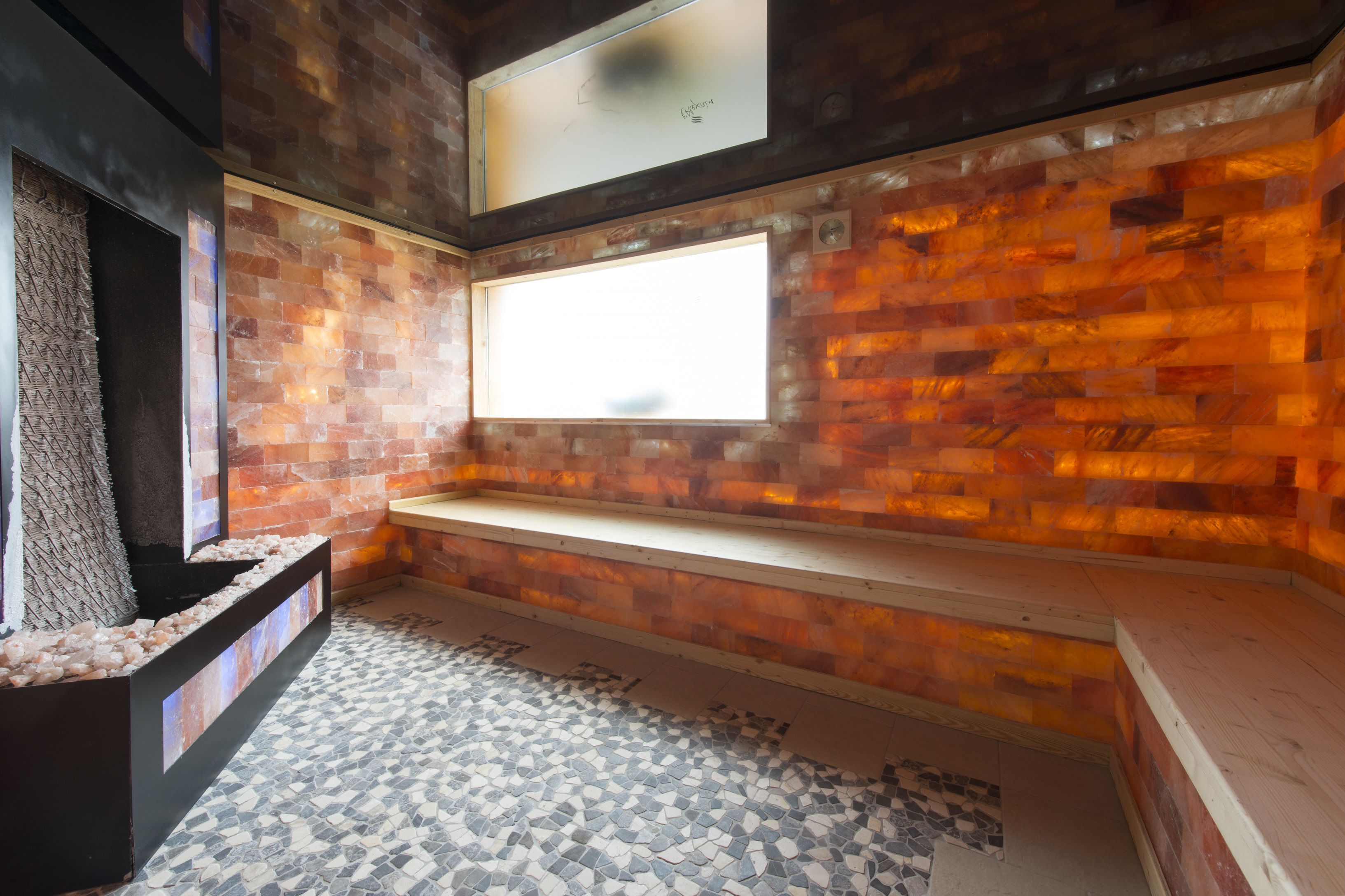A modern bathroom with a mosaic floor, a built-in bench, and a large window.