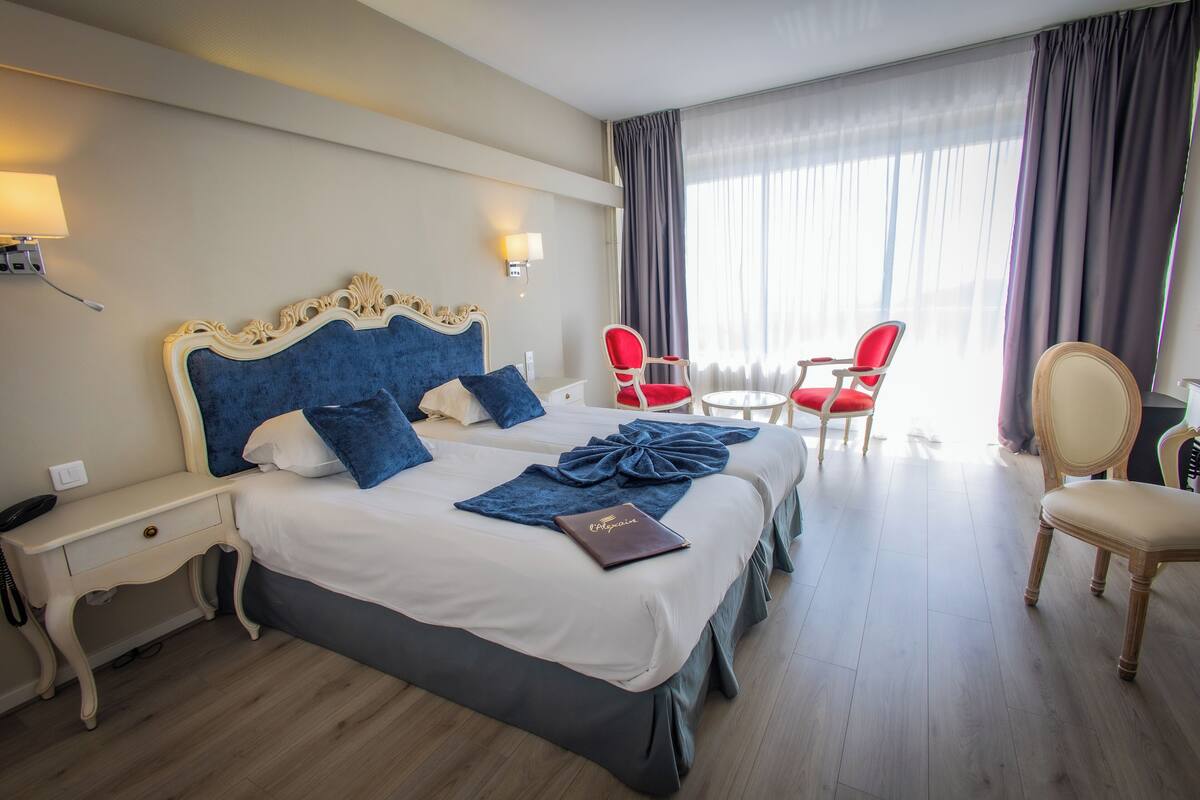 Una habitación de hotel con una cama grande, dos mesitas de noche, un escritorio y una silla.