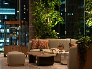 A modern living room with a sofa, ottoman, coffee table, and a glass display cabinet. - Mitsui Garden Hotel Sendai (Sendai)