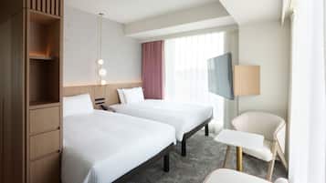 A hotel room with two beds, a TV, a desk, and a chair.
