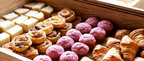A wooden box filled with various pastries including croissants, muffins, and other baked goods.