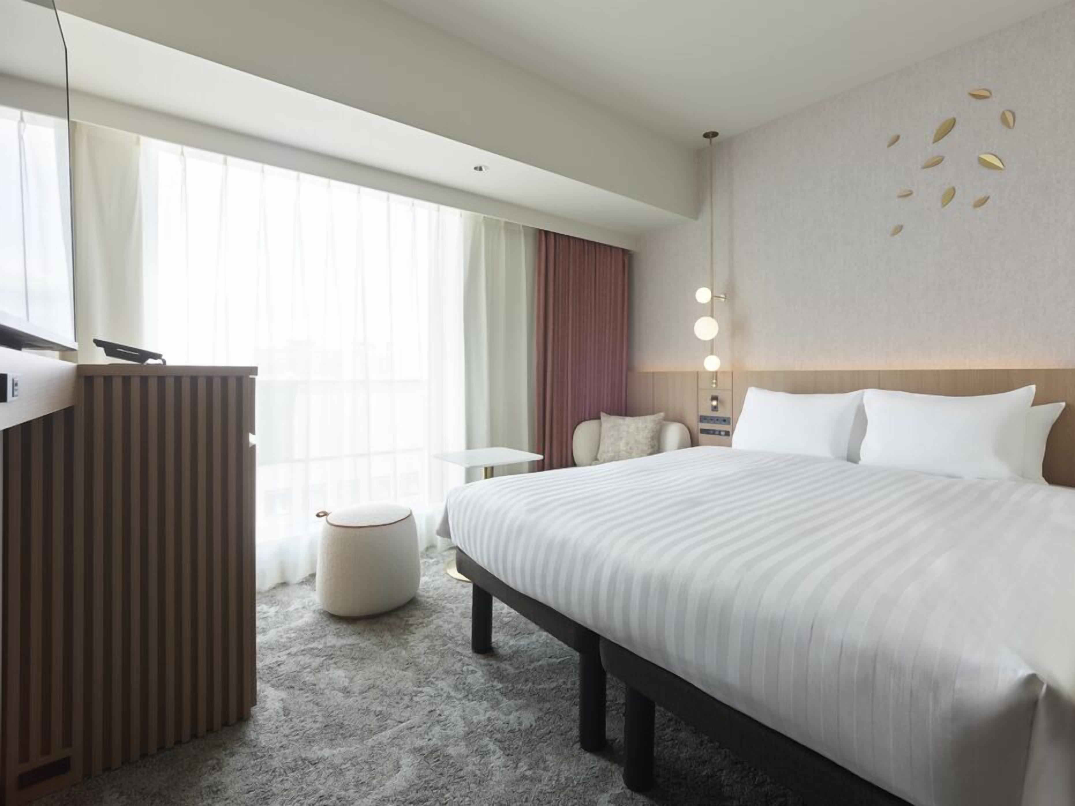 Habitación de hotel con una cama grande, un escritorio con una computadora, una mesita pequeña y una silla.
