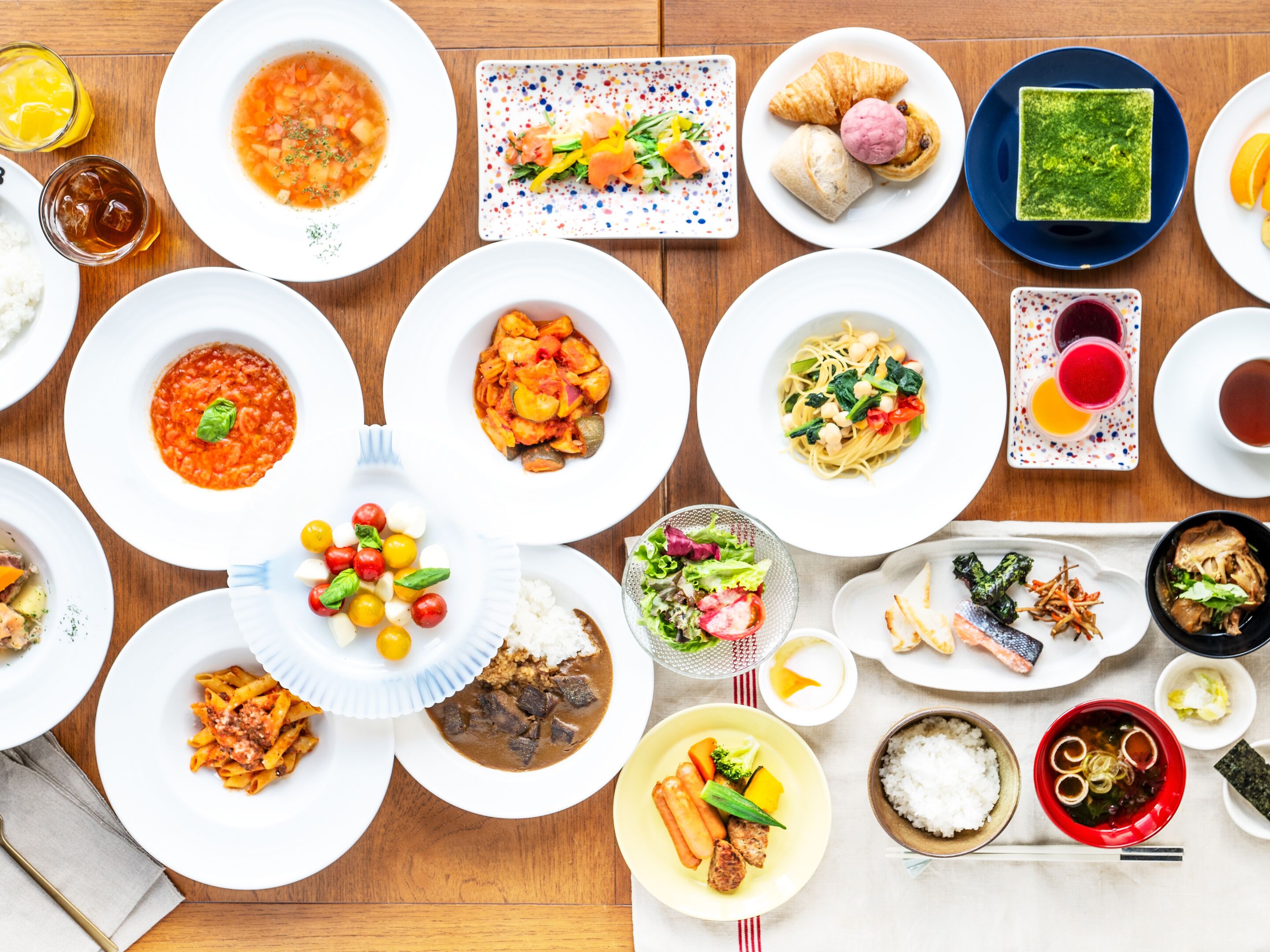 A variety of dishes and drinks on a wooden table.