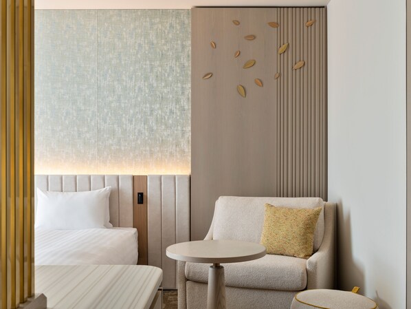Una habitación de hotel con una cama, un sofá, una mesita redonda y un panel decorativo en la pared.