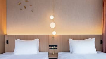 A hotel room with two beds, a wall-mounted light fixture, and a small table with a vase.