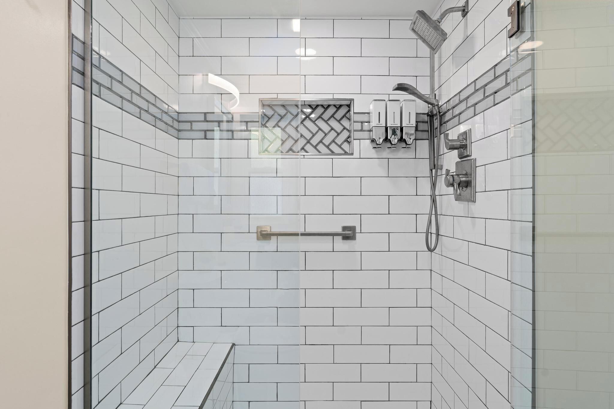 A modern bathroom with white subway tiles, a glass shower enclosure, a towel rack, and a showerhead.