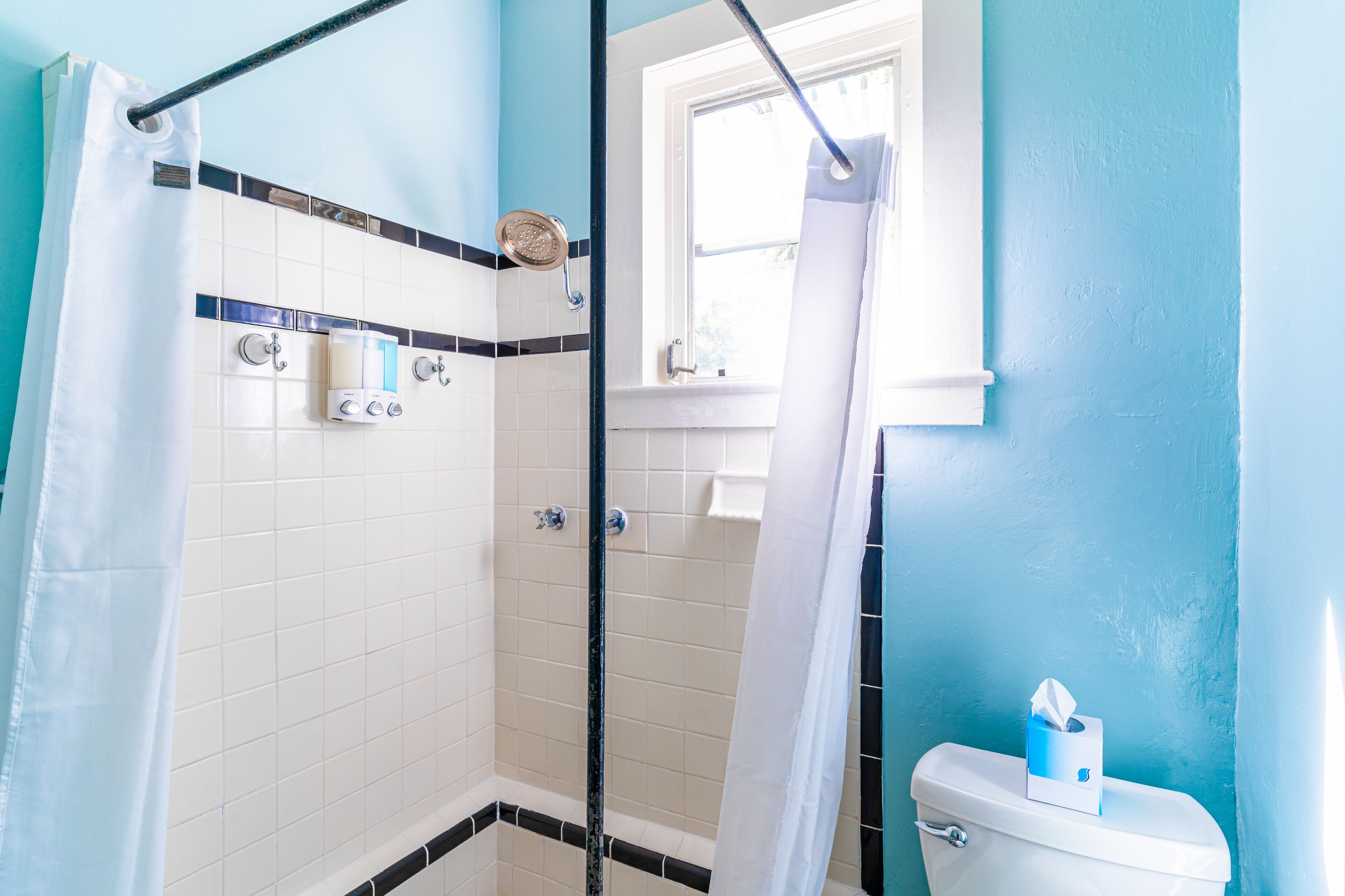 A bathroom with a shower, toilet, and a window.