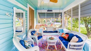 A bright, blue-walled porch with wicker furniture, a ceiling fan, and a view of the garden. - The Estate at Mount Dora (Mount Dora)