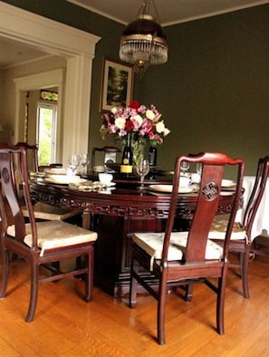 Un comedor con una mesa y sillas de madera, un candelabro y un jarrón con flores.