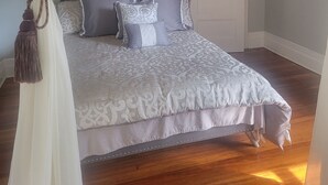 Un dormitorio con una cama grande, una araña, un espejo y una puerta.