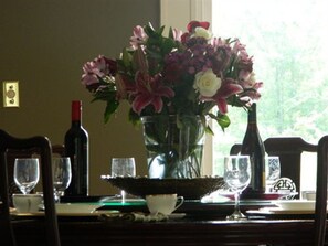 Enjoy meals in style with a beautifully set dining table, complete with a vase of flowers, wine, and fine glassware.