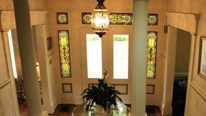 Un amplio pasillo con vidrieras decorativas, una columna central y un candelabro.