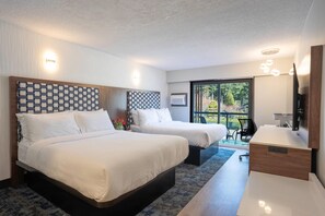 A hotel room with two beds, a desk, a chair, a TV, and a large window with a view of greenery. - Inn The Mountains, an Ascend Collection Hotel (Hope)