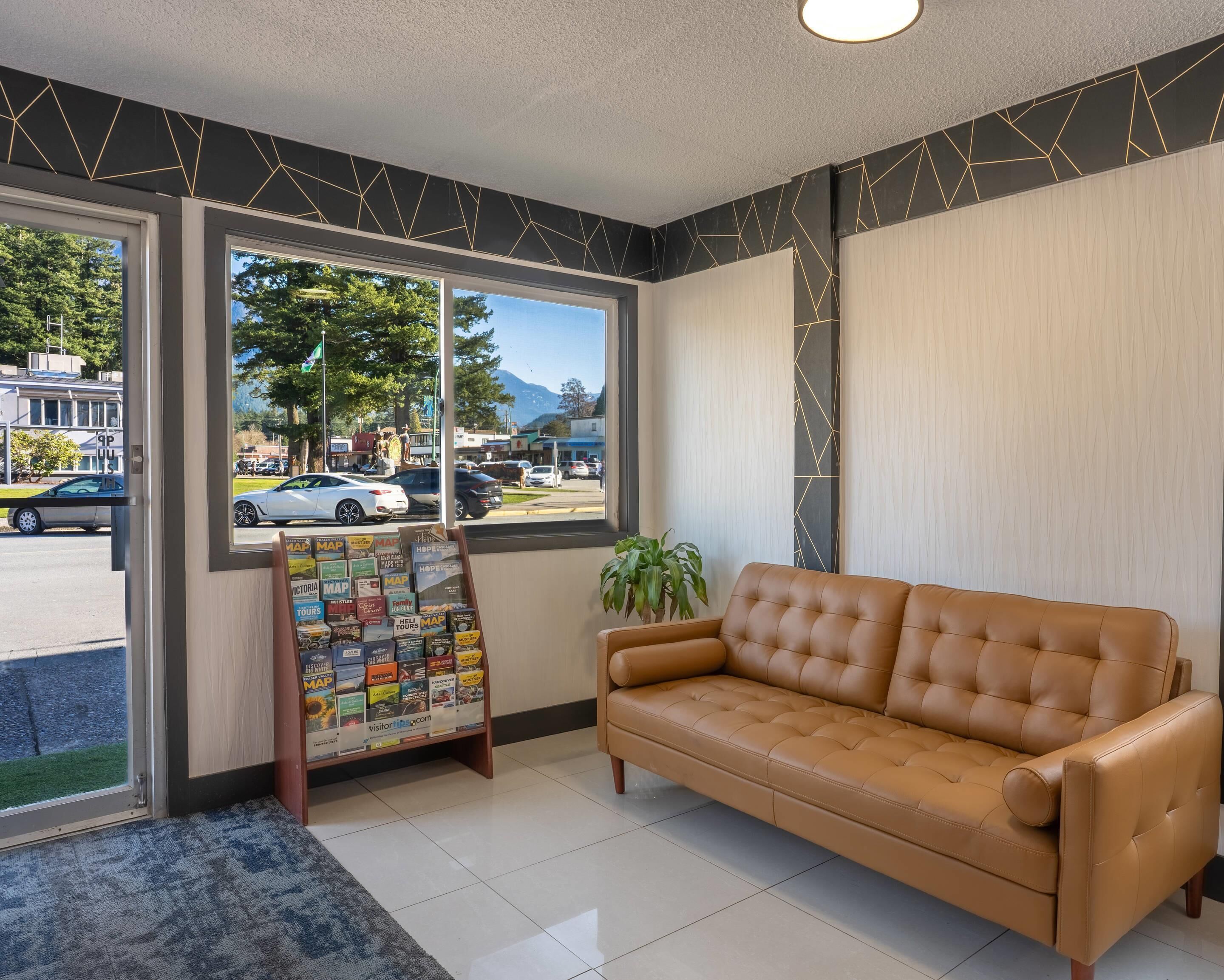 A room with a sofa, a map display, and a window with a view of the street and mountains.