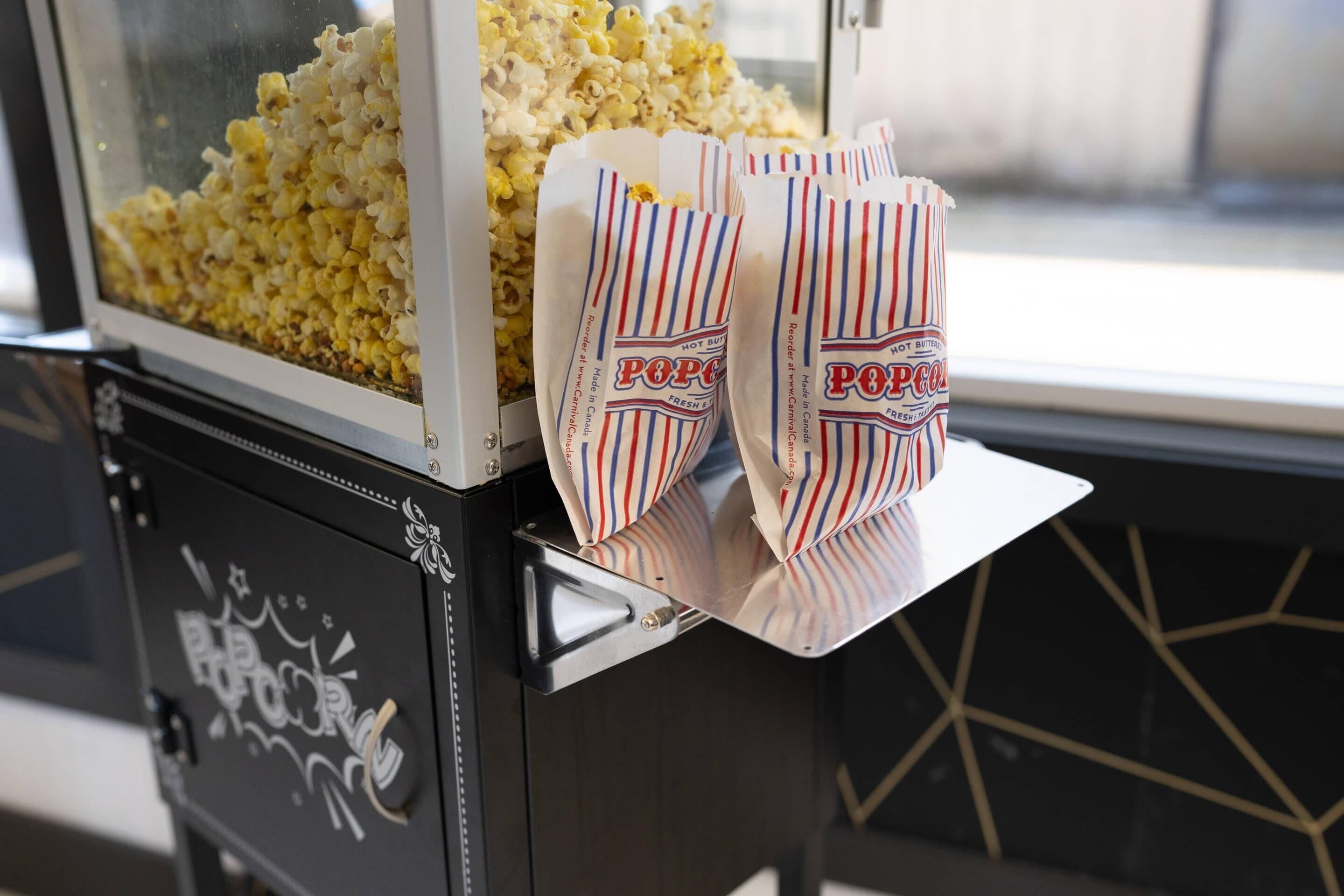 A popcorn machine with bags of popcorn and a window in the background.