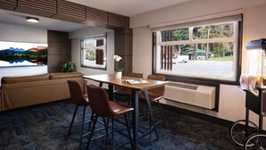 A modern room with a large window, a sofa, a table with chairs, and a radiator.