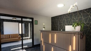 A reception desk with a modern design, a sofa, and a potted plant.