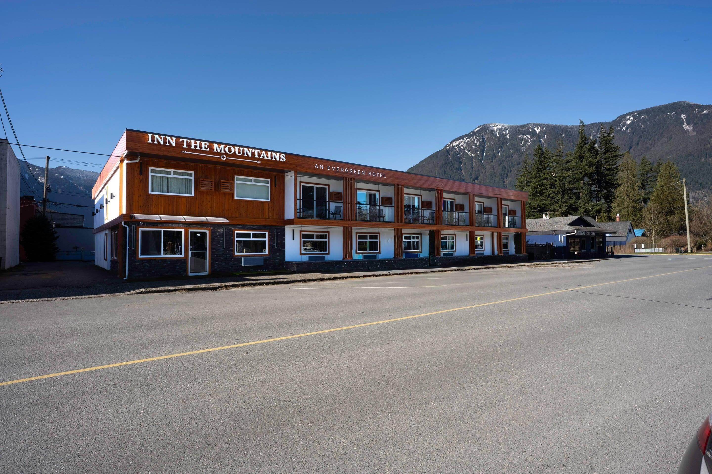 A two-story building with the sign 'INN THE MOUNTAINS' and 'AN EVERGREEN HOTEL' on the facade.