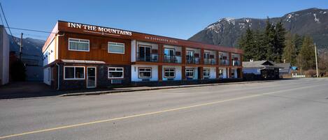 A two-story building with the sign 'INN THE MOUNTAINS' and 'AN EVERGREEN HOTEL' on the facade.