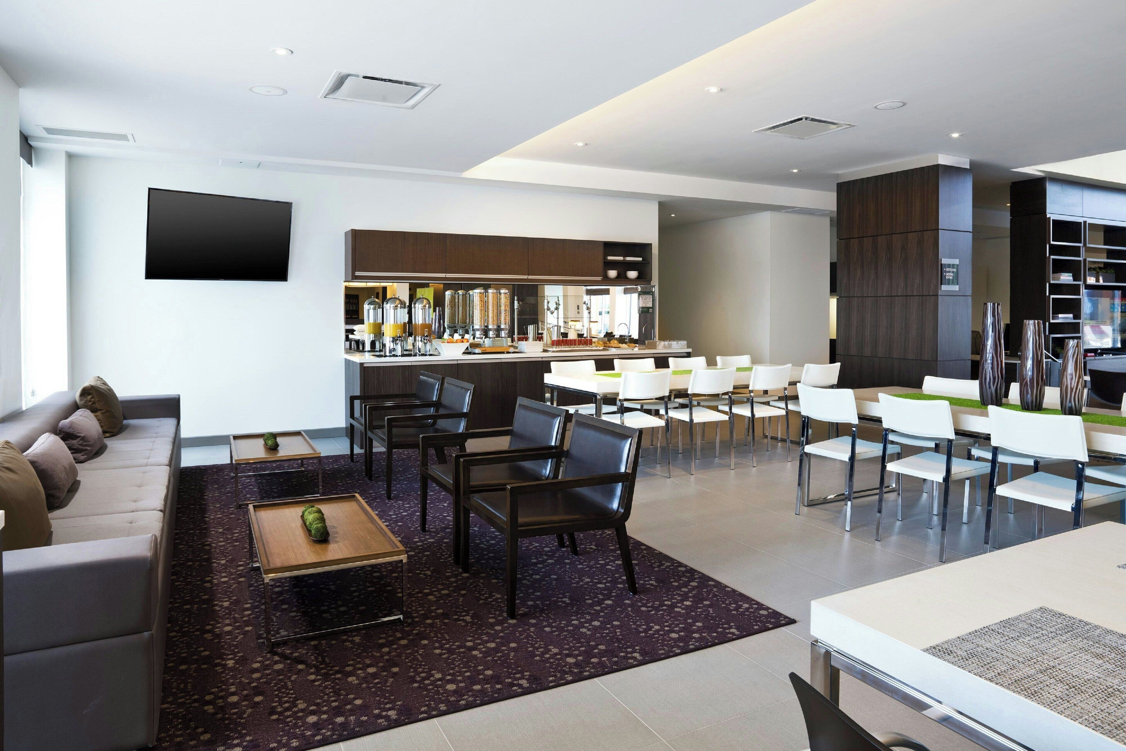 Un moderno vestíbulo de hotel con una zona de estar, un bar y una cocina al fondo.